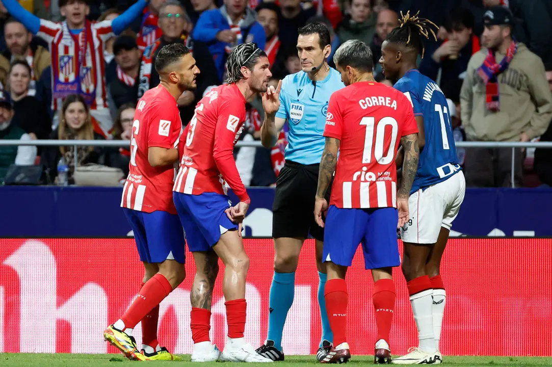 Jugadores del Atl&eacute;tico de Madrid conversan con el &aacute;rbitro Mart&iacute;nez Munuera durante un partido de la Liga espa&ntilde;ola. EFE/Mariscal