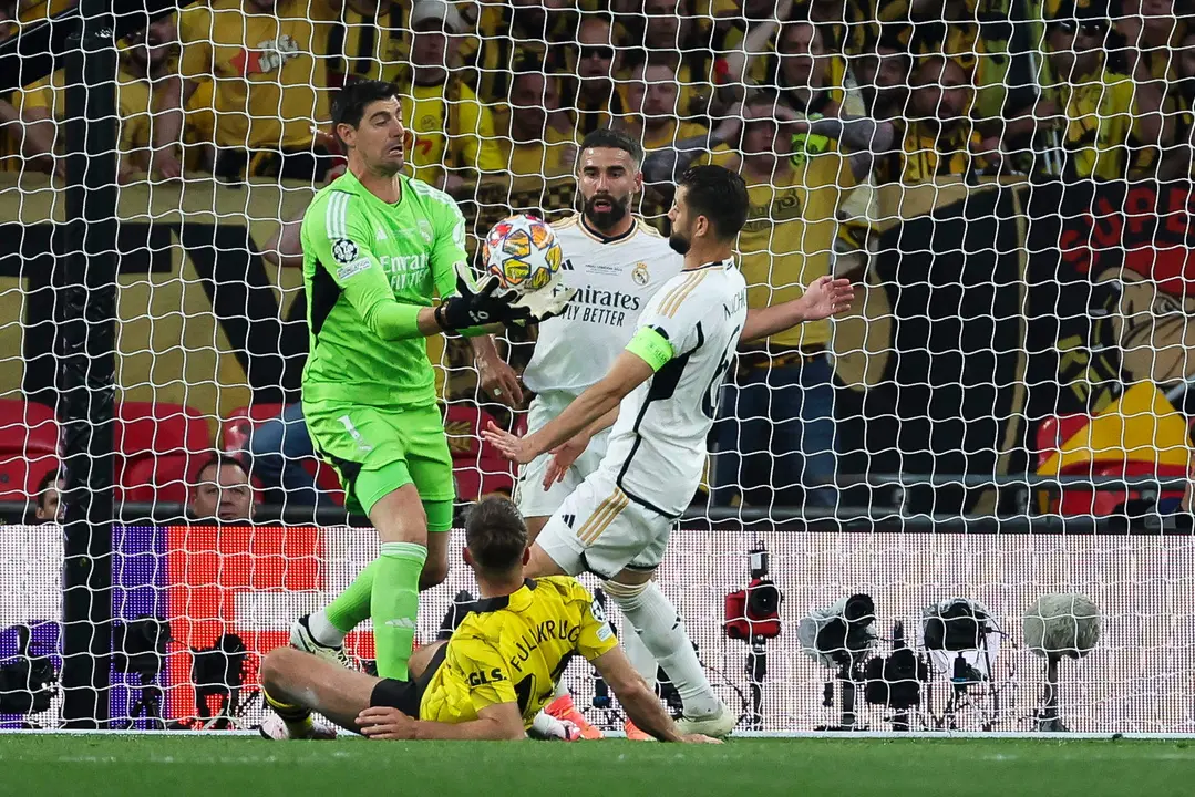 El guardameta belga del Real Madrid, Thibaut Courtois (i), captura el bal&oacute;n ante sus compa&ntilde;eros y el delantero del Borussia Dortmund, Niclas Fulkrug, durante el encuentro correspondiente a la final de la Liga de Campeones que Real Madrid y Borussia Dortmund disputaron en el estadio de Wembley, en Londres. EFE / Kiko Huesca.
