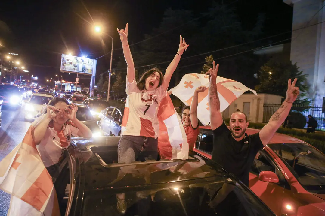Decenas de miles de aficionados se volcaron anche a la calles de Tiflis y otras ciudades de Georgia para celebrar hasta altas de la madrugada la victoria (2-0) de la selecci&oacute;n nacional sobre Portugal que le dio el pase a octavos de final del Eurocopa, donde le espera Espa&ntilde;a.En medio del estruendo de los fuegos artificiales y de los cl&aacute;xones de los autom&oacute;viles engalanados con la rojiblanca bandera del pa&iacute;s se o&iacute;an los gritos de j&uacute;bilo de los aficionados por el hist&oacute;rico logro del f&uacute;tbol georgiano en su primera participaci&oacute;n en un torneo continental.  EFE/ Misha Vignanski.